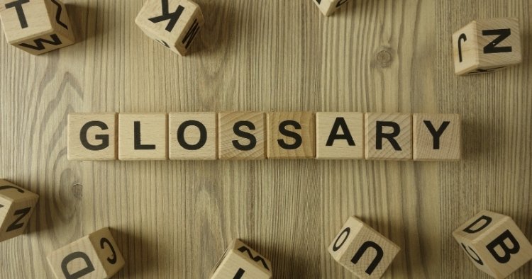 "Glossary" spelled out by Scrabble tiles on a wooden table